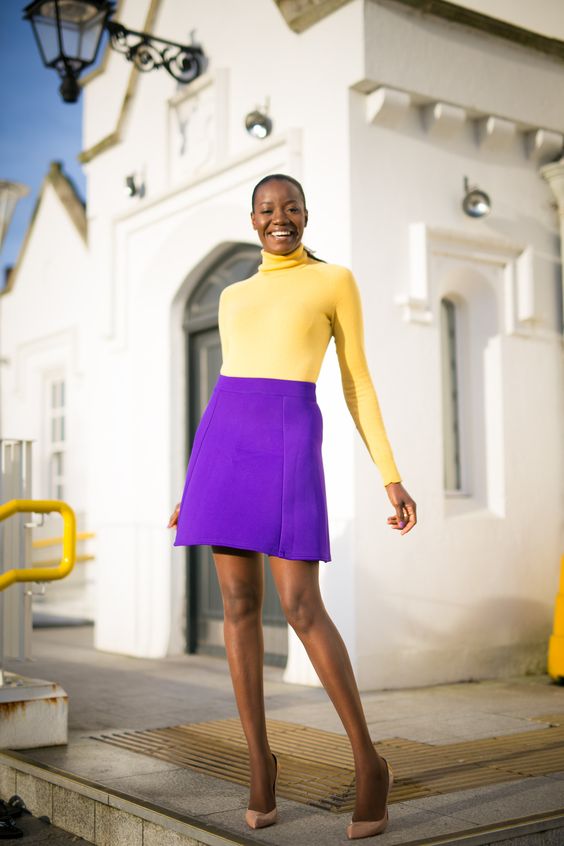 yellow turtleneck sweater with a purple mini skirt as fashionable color clash outfit